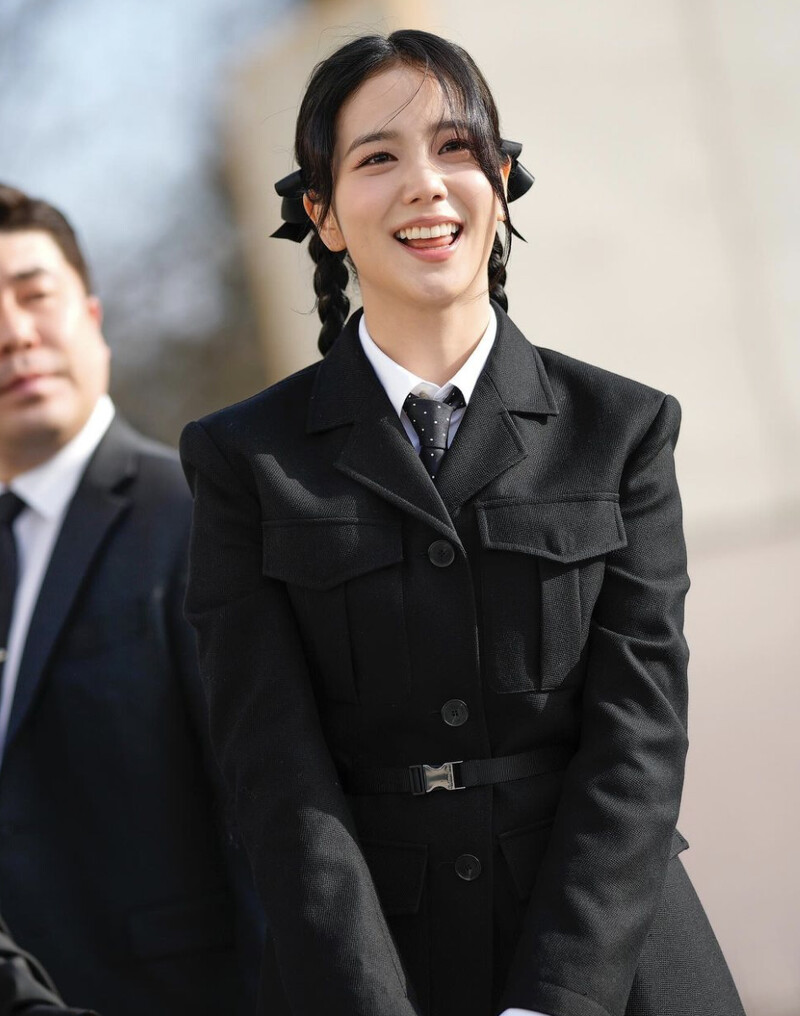 Jisoo 以黑色西裝外套搭配小短褲,造型上以小圓點的領帶,蝴蝶結雙辮髮型最為造型焦點,時髦度極高。