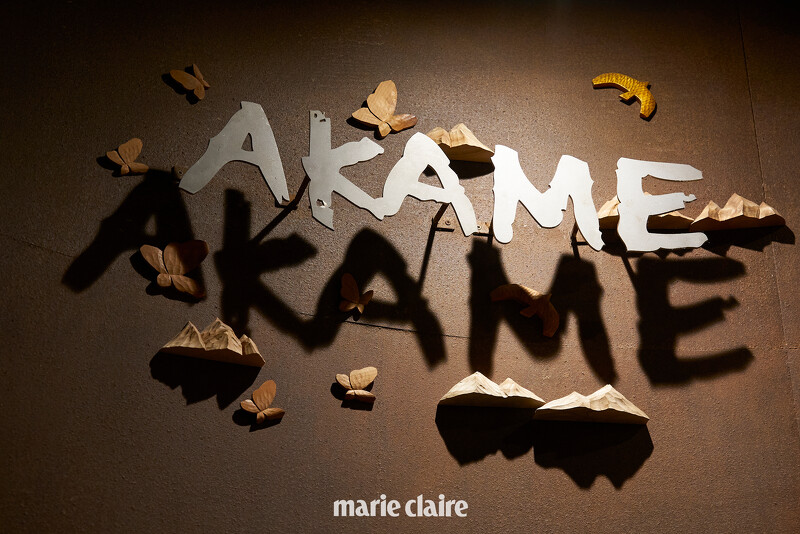 餐廳牆面大大的「AKAME」字樣旁裝飾著由臺中老字號木雕店「陳雕刻處」所製作的木雕蝴蝶、飛鳥,以及象徵九週年的「山」形雕刻。