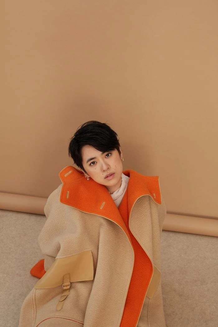 白高領透膚上衣 LOEWE；雙色駱駝斗篷大衣、米色馬褲、小牛皮長靴All by HERMÈS；幾何金耳扣、圓圈線條耳扣、圈形金耳環、字母線條戒指、金色戒指All by APM MONACO。