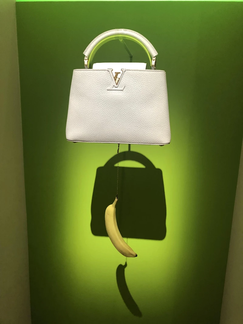 Urs Fischer的作品，以現代藝術戲謔的手法將香蕉吊於包款下方，大鬧時尚，卻也似藝術作品。其底下的香蕉可以換成蘋果或其他水果，這是真的不是笑話喔。