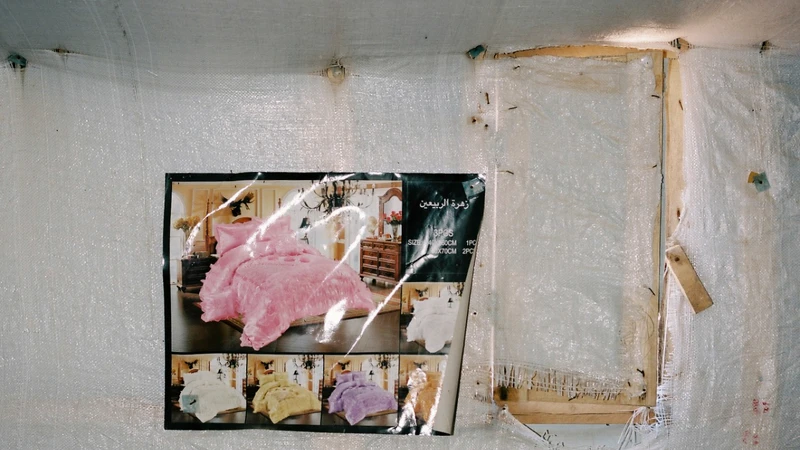 一對新婚夫妻在難民營陰暗且空蕩蕩的帳篷裡,掛著一幅華麗大床的照片。 一對新婚夫妻在難民營陰暗且空蕩蕩的帳篷裡,掛著一幅華麗大床的照片。