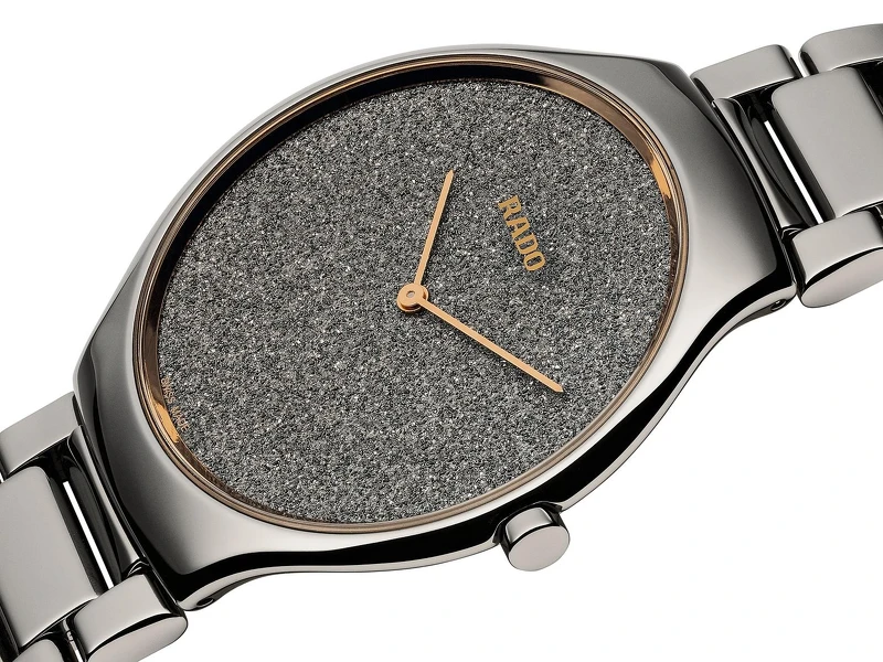 True Thinline 真我超薄亮鑽系列亮鑽系列錶盤以電鍍工藝對鑽石粉末的晶體結構進行複製打造，誕生出特殊的紋理結構，不同顏色的鑽石晶體依角度變化折射出耀眼的光芒， 腕錶面盤移除時標，則提升造型美學與現代感！