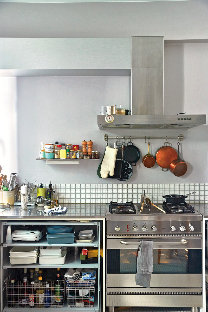 在牆面放上跟檯面一樣不鏽鋼材質的層板，把常用的調味料放在上面，以瓶身後高前低的擺法就可以清楚取用。