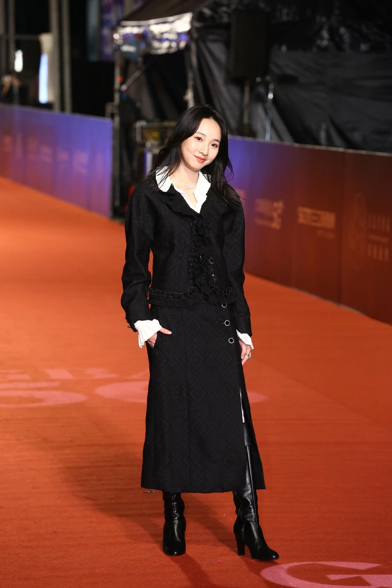 李沐身著Chanel 20/21工坊系列服飾:黑色羊毛真絲緹花,飾以刺繡荷葉緄邊外套與同款及膝開岔裙,配上率性的黑色皮革長靴。 李沐身著Chanel 20/21工坊系列服飾:黑色羊毛真絲緹花,飾以刺繡荷葉緄邊外套與同款及膝開岔裙,配上率性的黑色皮革長靴。