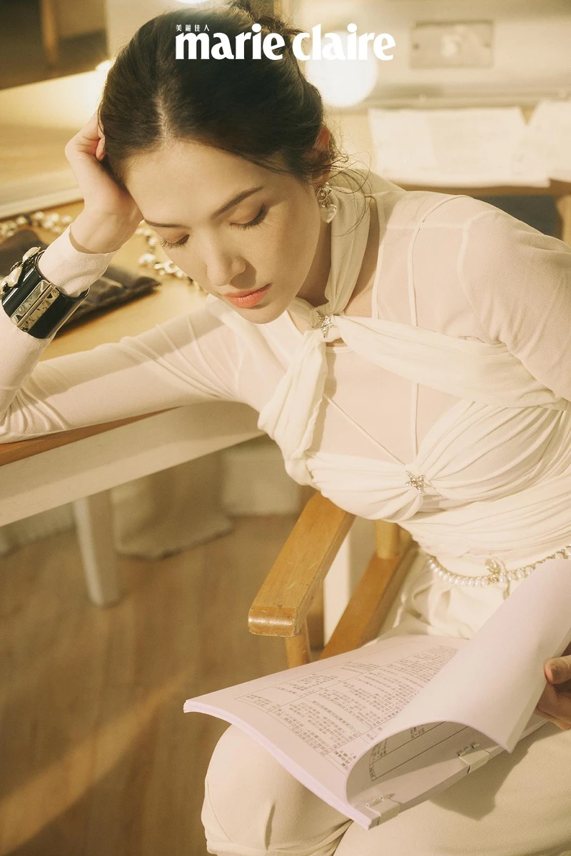 白色真絲縐紗綁帶造型上衣與同款長褲、 雙色皮革短靴、黑色高級樹脂馬爾他十字手環、金屬高級樹脂愛心造型耳環、金屬幻象珍珠腰鍊，all by CHANEL。