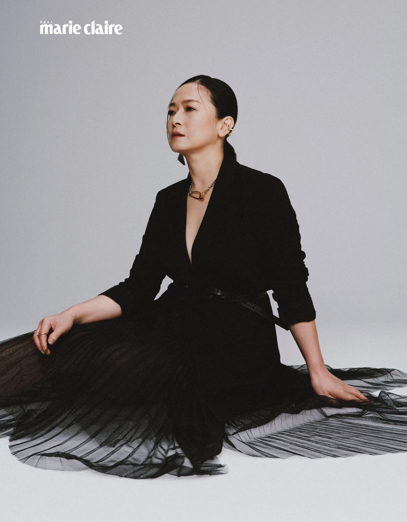 黑色西裝外套、黑色紗裙、黑色窄版皮帶；all by Allsaints；金色項鍊、金色耳骨夾，both by VANN；綠色耳環，Prada。