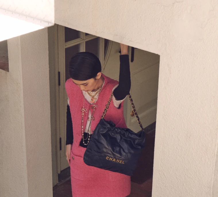 黑白拼接上衣、粉色斜紋軟呢背心、粉色斜紋軟呢半身裙、CHANEL 22包、服飾珠寶配件,All by CHANEL。 黑白拼接上衣、粉色斜紋軟呢背心、粉色斜紋軟呢半身裙、CHANEL 22包、服飾珠寶配件,All by CHANEL。