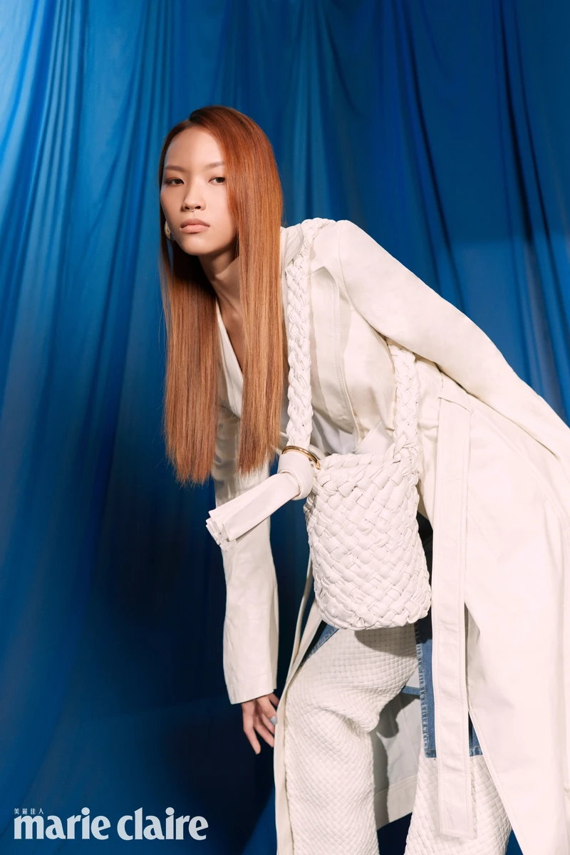 白色皮革風衣、白色背心、皮革丹寧短裙、白色編織高跟長靴、白色編織牛皮肩背包、耳環；all by Bottega Veneta。