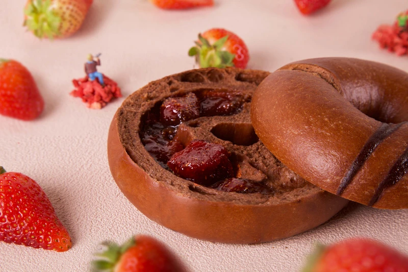 「草莓巧克力」貝果滿滿法國歌劇 L_Opera 巧克力香氣，濃厚略帶質感苦甜，襯托手工自製草莓內餡圓滿甜蜜；最後再澆淋巧克力甘納許點綴視覺美感