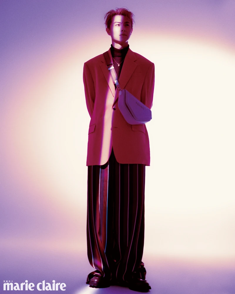 粉色西裝外套、紅色條紋寬鬆長褲、金色項鍊，all by Versace；酒紅色高領針織衫，John Varvatos；白色側背包、深綠色樂福鞋，both by PEDRO