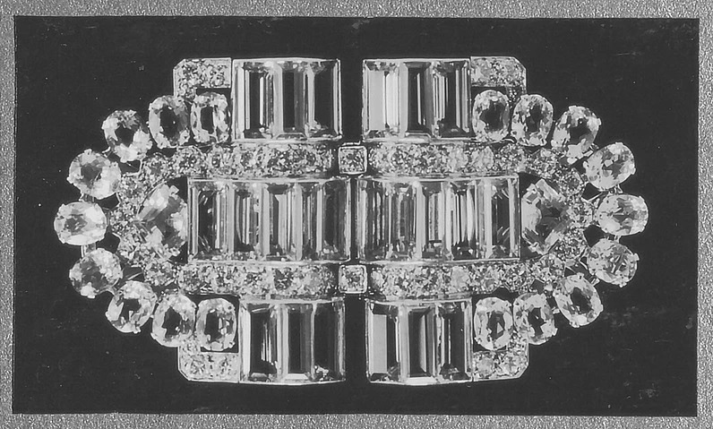 Boucheron 啟發自歷史檔案中一件已逝英國女王本人，在她18歲之時所收受的一件由寶詩龍設計製作的Art Deco 風格之海藍寶石鑽石雙夾胸針