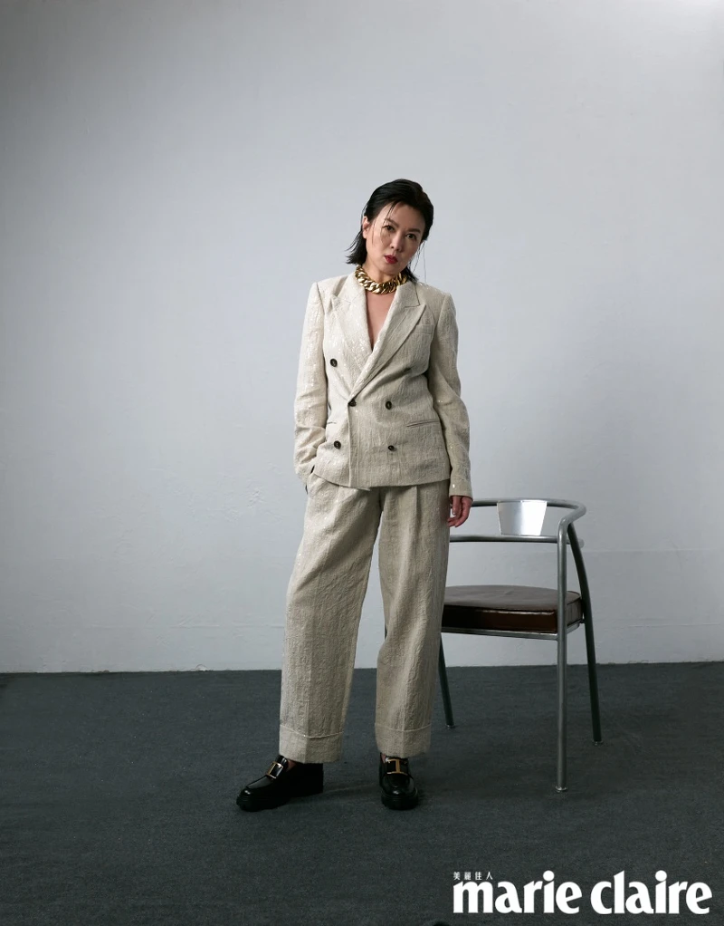 米色西裝外套、黑色內搭背心、米色西裝長褲，all by Brunello Cucinelli；黑色皮革樂福鞋，Tod’s；金色項鍊，Recovery。