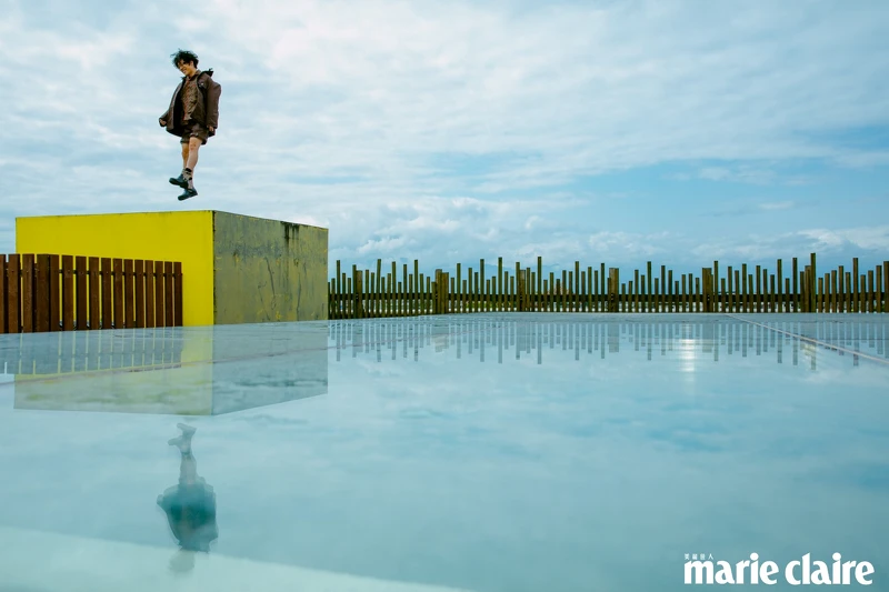 咖啡色圖紋襯衫、Oversize Parka 外套、扣飾皮革短褲、異材質拼接短靴，all by Coach。