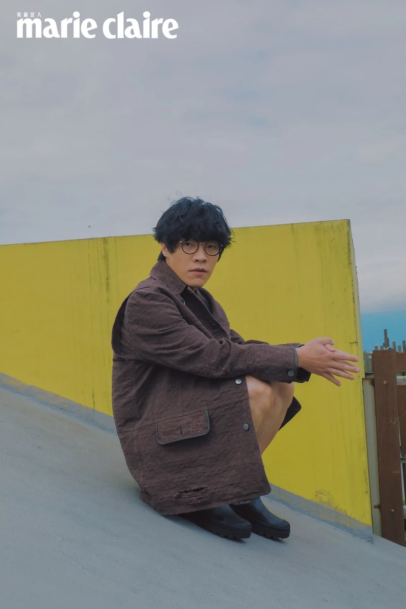 咖啡色圖紋襯衫、Oversize Parka 外套、扣飾皮革短褲、異材質拼接短靴，all by Coach。