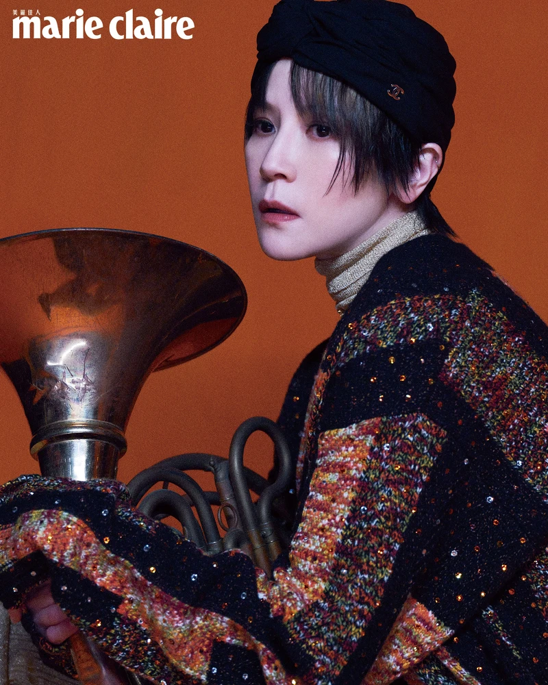 金色高領針織上衣、金色針織長褲、橘色拼接針織背心、橘色拼接針織外套、橘色串珠腰鍊、黑色帽飾，all by CHANEL。