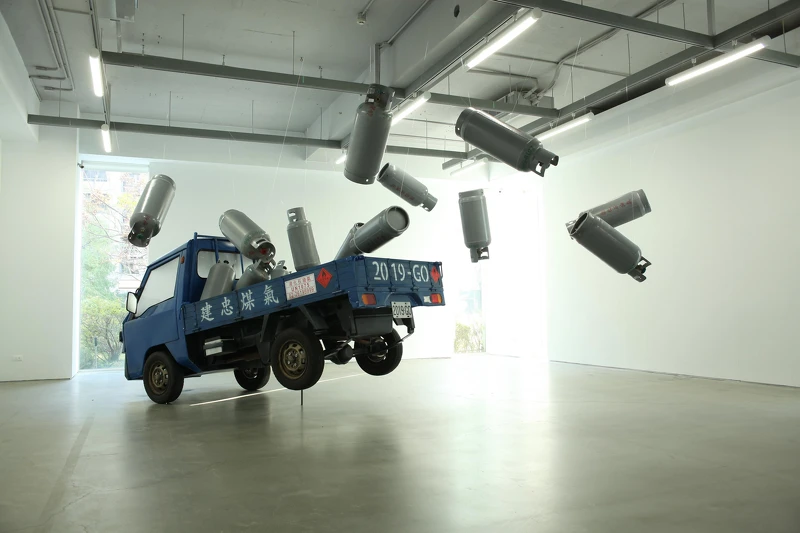 廖建忠讓沉重的瓦斯桶與小卡車如失去重力般飛躍起來,作品〈載瓦斯的小發財〉。廖建忠提供。 廖建忠讓沉重的瓦斯桶與小卡車如失去重力般飛躍起來,作品〈載瓦斯的小發財〉。廖建忠提供。