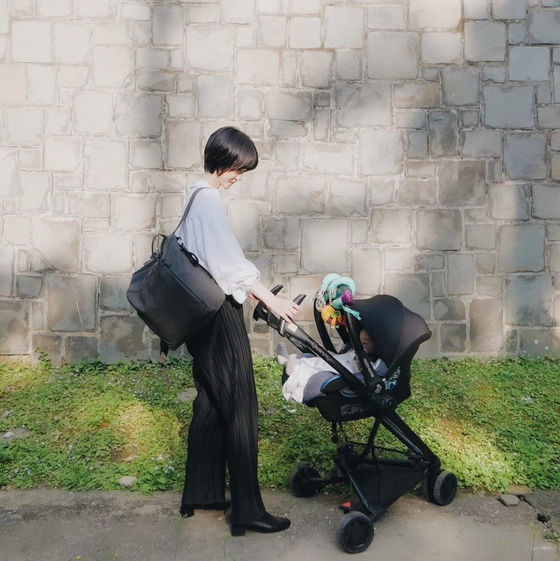 Hannah喜愛碳灰黑純色質感皮革後背媽媽包,可以方便掛在推車上,皮革質感的簡約設計能夠兼顧質感穿搭。 Hannah喜愛碳灰黑純色質感皮革後背媽媽包,可以方便掛在推車上,皮革質感的簡約設計能夠兼顧質感穿搭。