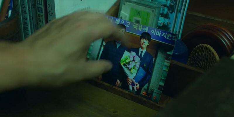 全永錫在陌生人出現時，警覺地把和兒子的合照蓋上