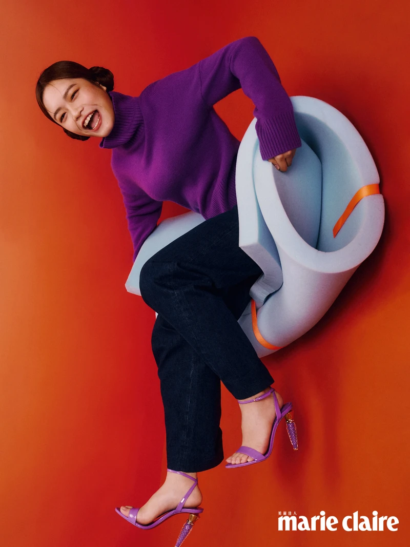 高領針織上衣，Maje；深藍色丹寧褲，Sandro；紫色漆皮高跟鞋，Christian Louboutin。