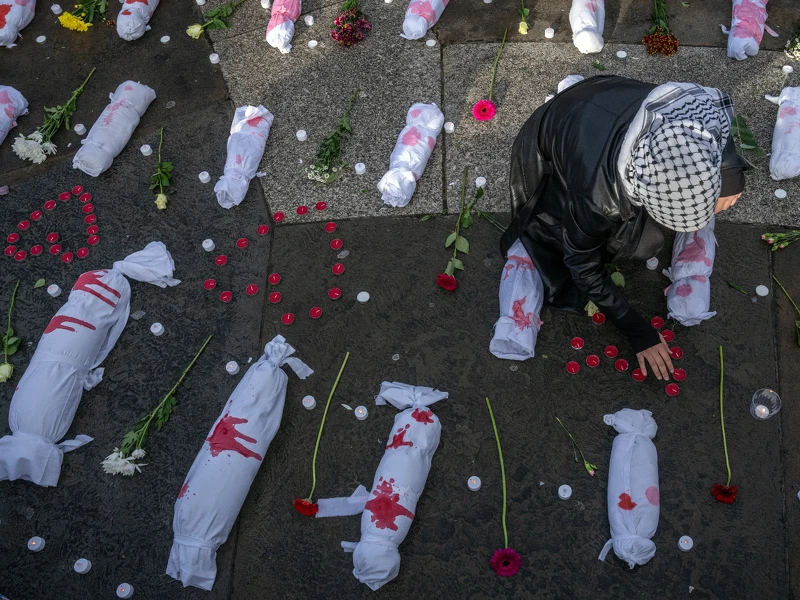 英國倫敦,一場呼籲哈馬斯和以色列停火的抗議活動中,一名女性在代表死嬰的小包束中整理蠟燭。 英國倫敦,一場呼籲哈馬斯和以色列停火的抗議活動中,一名女性在代表死嬰的小包束中整理蠟燭。