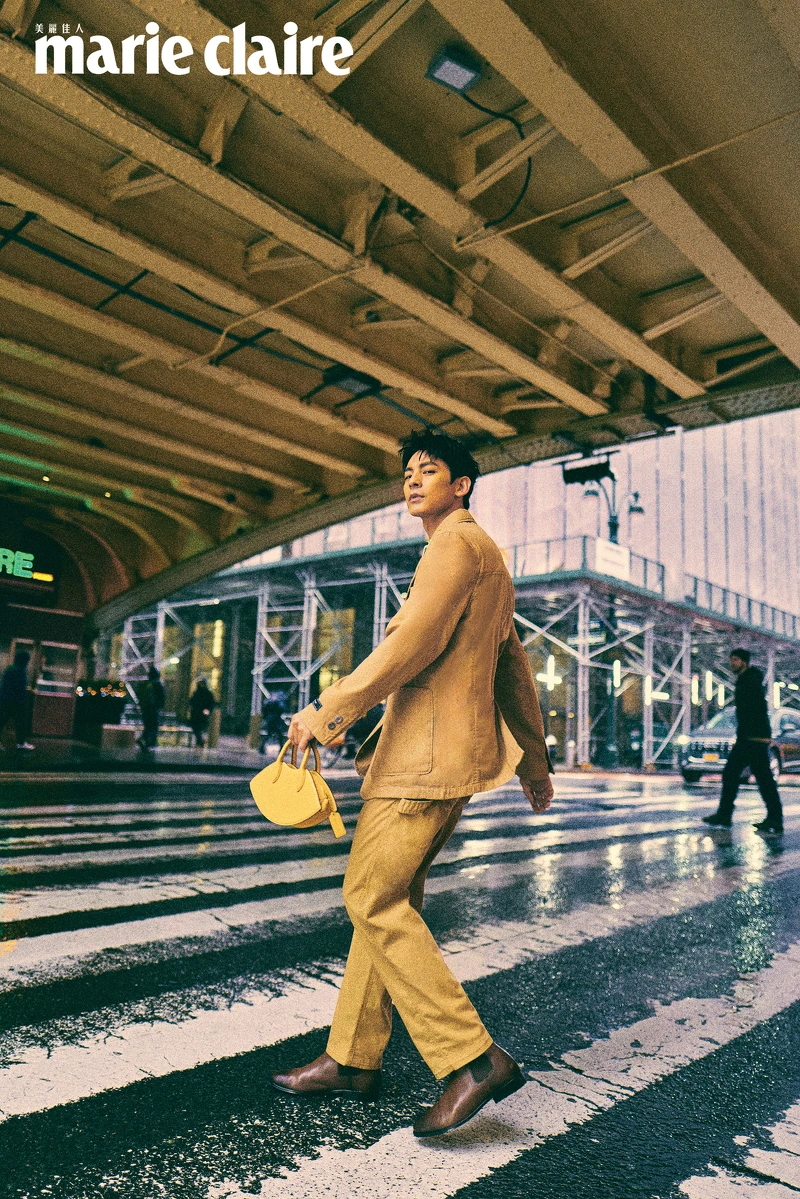 卡其色西裝外套、卡其色西裝長褲、咖啡色皮質長靴、蒼蠅恐龍不對稱胸針、絎縫鴨子造型手袋，all by Coach。