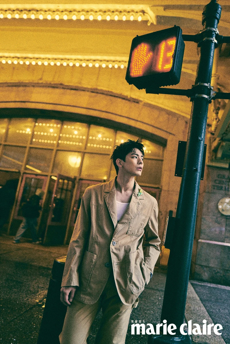 卡其色西裝外套、卡其色西裝長褲、咖啡色皮質長靴、蒼蠅恐龍不對稱胸針，all by Coach。