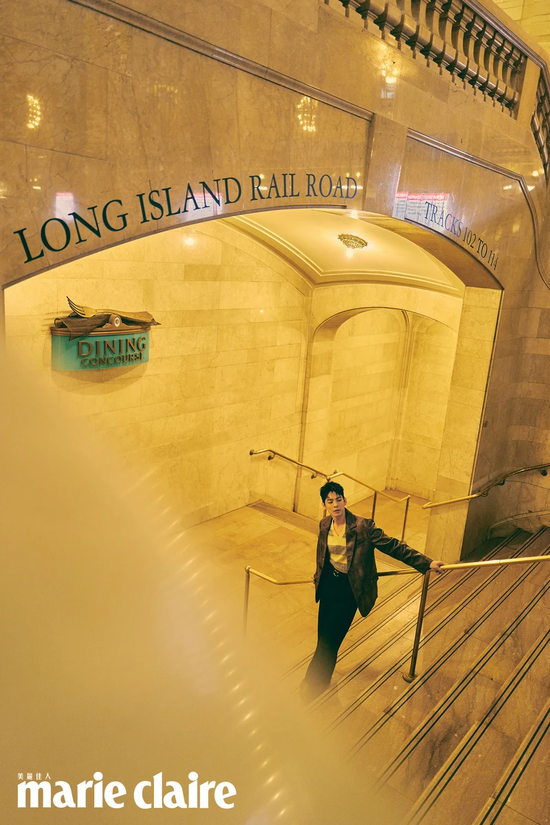 咖啡色皮質西裝外套、黃色條紋背心、皮帶、黑色西裝寬褲、咖啡色皮質長靴，all by Coach。