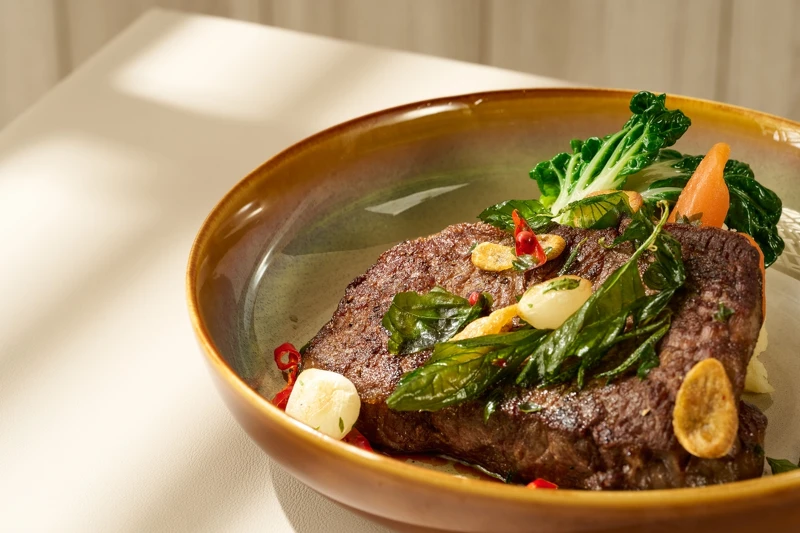 「美國極黑牛戰斧牛排」，佐以蒜片和九層塔。