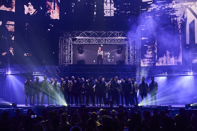 《角頭》中飾演「仁哥」的王識賢，站在二樓舞台獨唱，俯瞰電影中人氣組合「五虎將」成員鄭人碩、張再興、黃尚禾、吳震亞與唐振剛，以及大批黑衣人在現場飆戲爭鬥