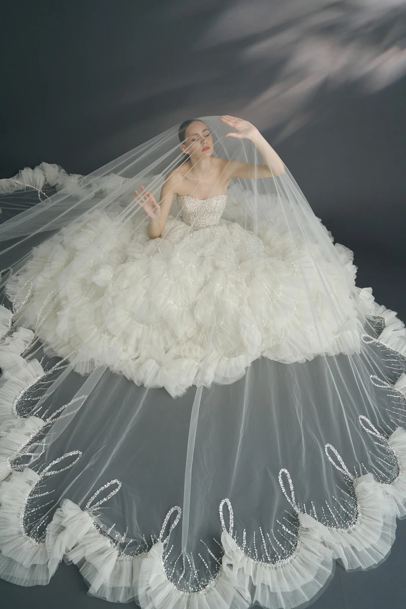 壓褶荷葉白紗《Narcissus 水仙花》,以菱格設計延伸至裙擺的圓弧交錯圖騰。(LinLi Boutique 提供) 壓褶荷葉白紗《Narcissus 水仙花》,以菱格設計延伸至裙擺的圓弧交錯圖騰。(LinLi Boutique 提供)