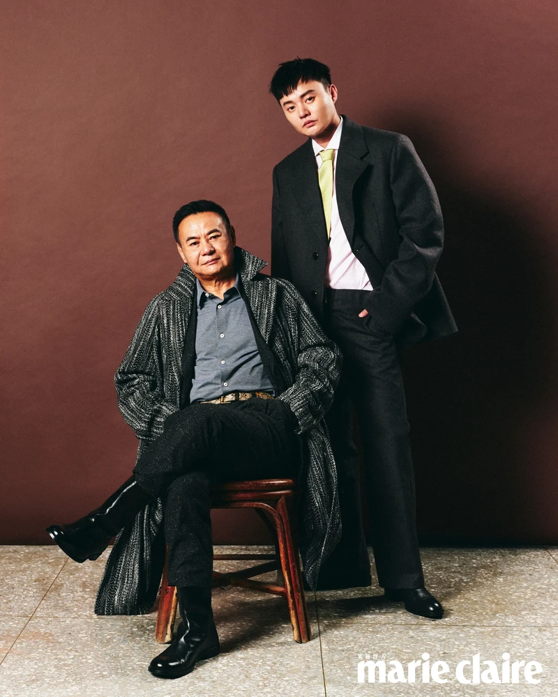 蔡振南／灰色襯衫、黑色西裝外套、格紋長版大衣、黑色西裝褲，all by Boss；黑色皮鞋，Bottega Veneta。許富凱／鐵灰色羊毛西裝外套、淺粉色撞色衣領襯衫、鐵灰色羊毛長褲、綠色絲質領帶，all by Prada；黑色短靴，Boss。