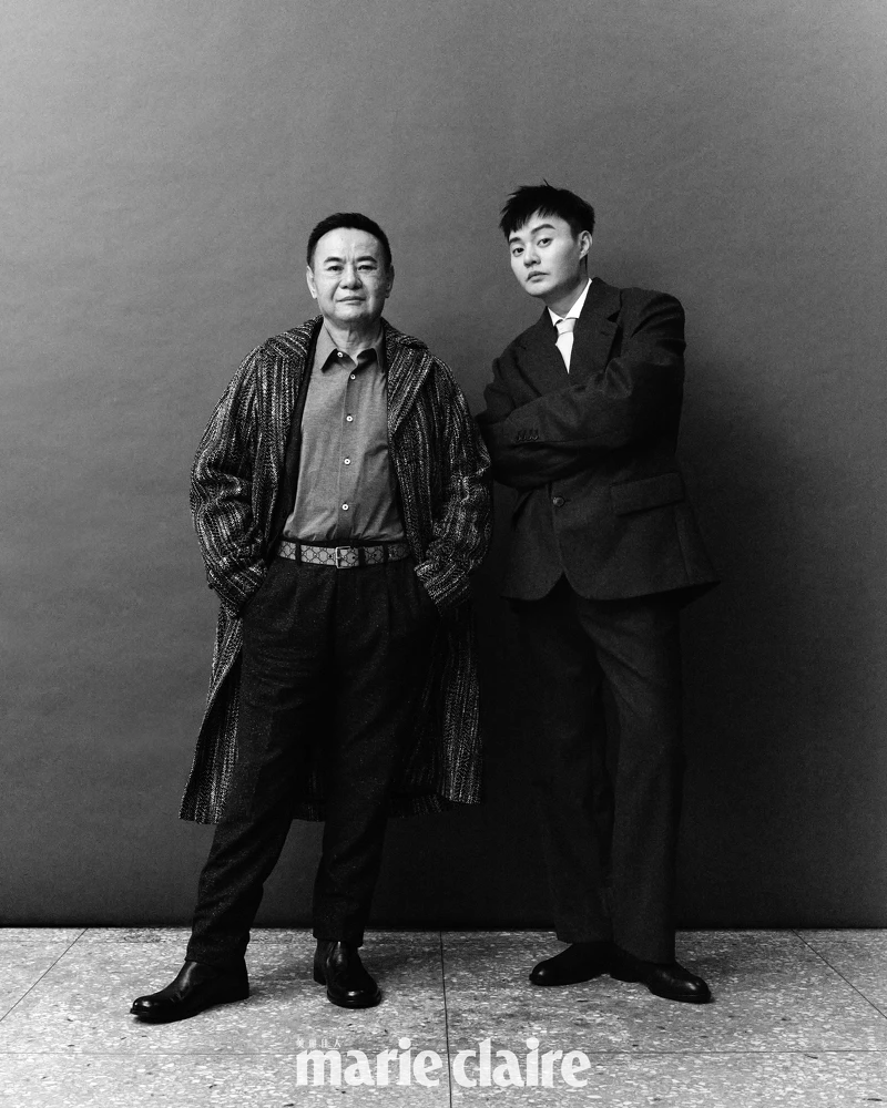 蔡振南／灰色襯衫、黑色西裝外套、格紋長版大衣、黑色西裝褲，all by Boss；黑色皮鞋，Bottega Veneta。許富凱／鐵灰色羊毛西裝外套、淺粉色撞色衣領襯衫、鐵灰色羊毛長褲、綠色絲質領帶，all by Prada；黑色短靴，Boss。