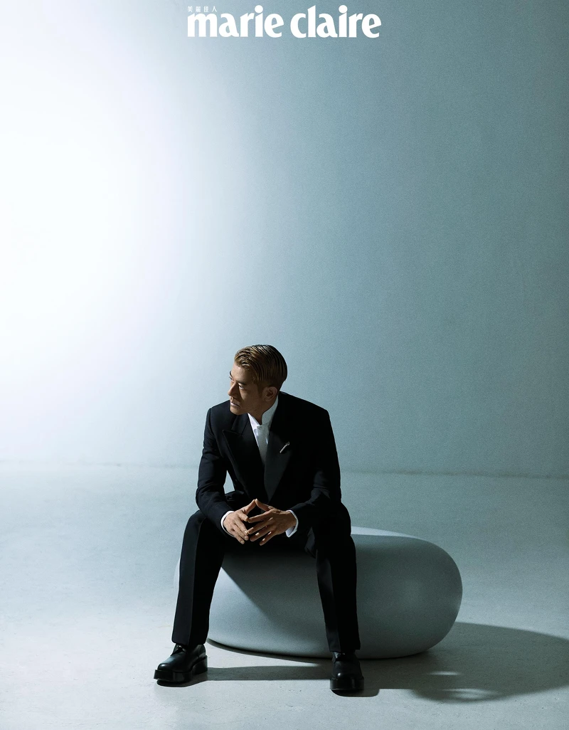 黑色羊毛和絲綢雙排扣西裝、白色棉質立領襯衫、黑色羊毛和絲綢西裝褲,all by Loro Piana;銀色扭結胸針、黑色皮靴,both by Bottega Veneta。 黑色羊毛和絲綢雙排扣西裝、白色棉質立領襯衫、黑色羊毛和絲綢西裝褲,all by Loro Piana;銀色扭結胸針、黑色皮靴,both by Bottega Veneta。