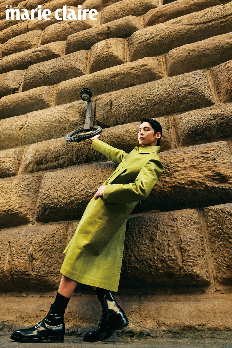 芥末黃皮大衣、綠色鏤空上衣、黑色短褲、Horsebit腰帶、Burn短靴、項鍊， All by Gucci。