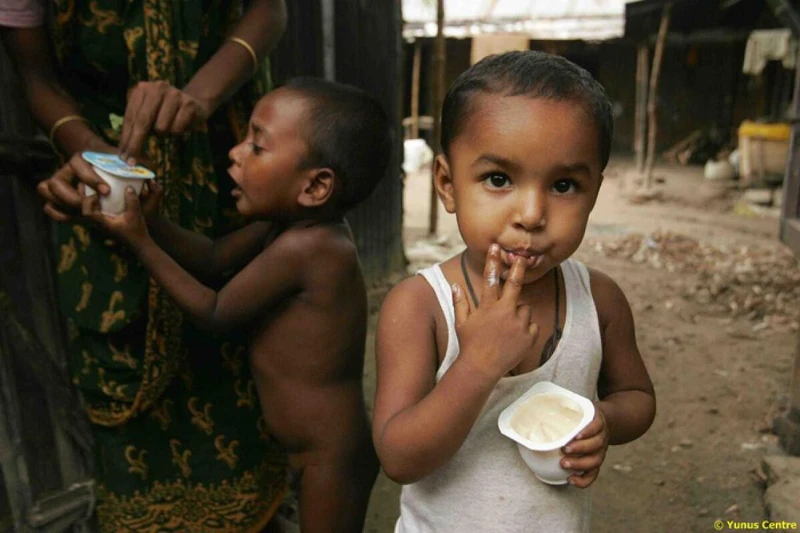 眼睛睜大的小童吃著台幣2元優酪乳 Grameen Danone。