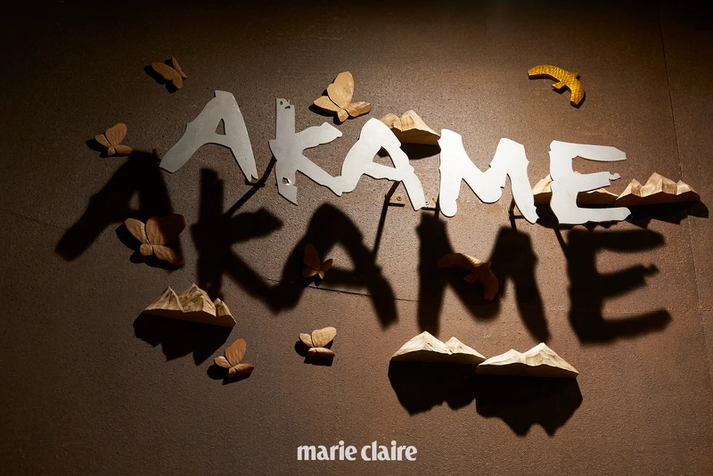 餐廳牆面大大的「AKAME」字樣旁裝飾著由臺中老字號木雕店「陳雕刻處」所製作的木雕蝴蝶、飛鳥,以及象徵九週年的「山」形雕刻。 餐廳牆面大大的「AKAME」字樣旁裝飾著由臺中老字號木雕店「陳雕刻處」所製作的木雕蝴蝶、飛鳥,以及象徵九週年的「山」形雕刻。