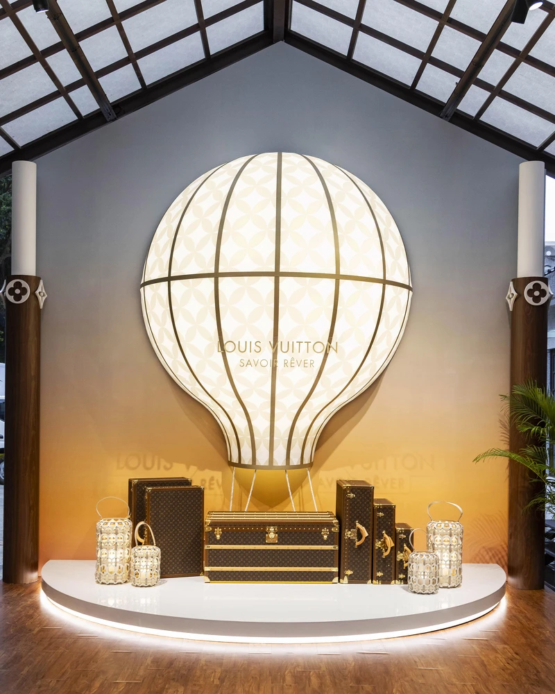以Monogram花朵發光為設計的熱氣球設計與經典硬箱裝置展現了升空高飛的旅行概念。
