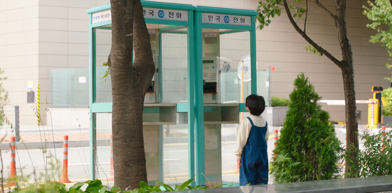 一個小男孩盯著空空的電話亭看著 一個小男孩盯著空空的電話亭看著