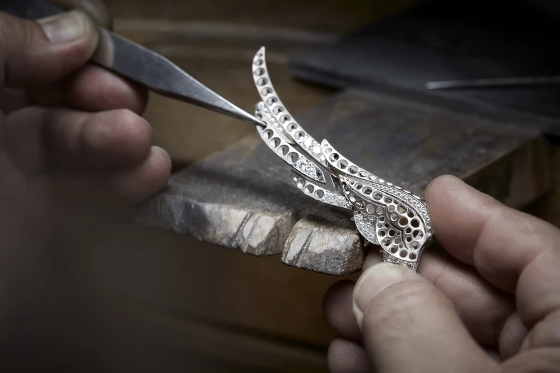 將部分完成鑲嵌的羽毛組裝於 EMBRACE YOUR DESTINY 項鍊的左翼上。