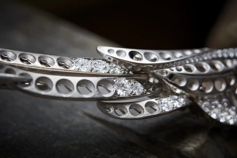 將部分完成鑲嵌的羽毛組裝於 EMBRACE YOUR DESTINY 項鍊的左翼上。